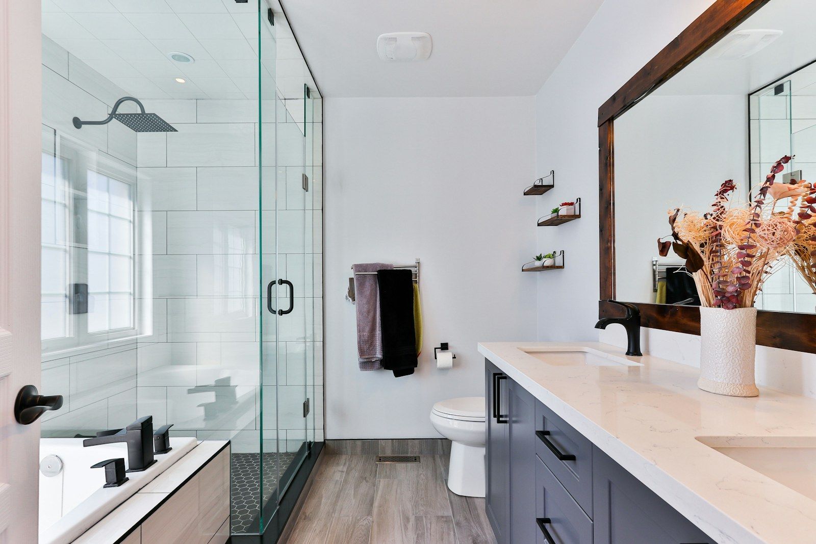 Renoviertes Badezimmer mit Glasdusche, Waschtisch und Holzspiegel