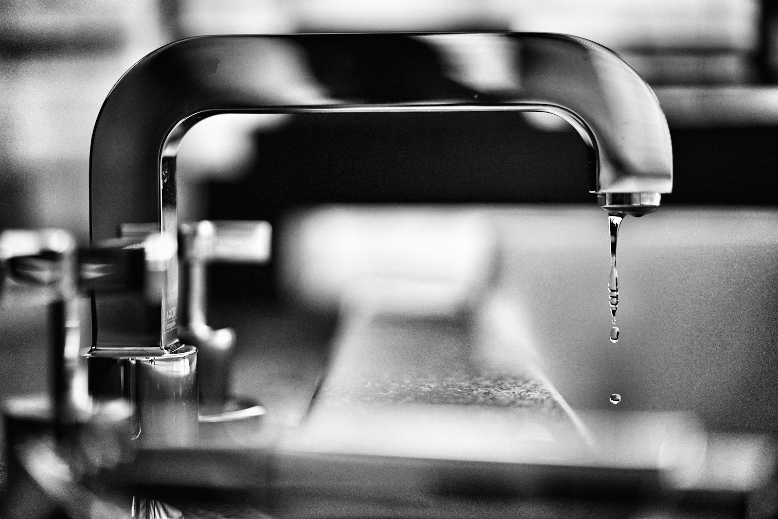 Wassertropfen löst sich von einem Wasserhahn, Schwarzweißaufnahme